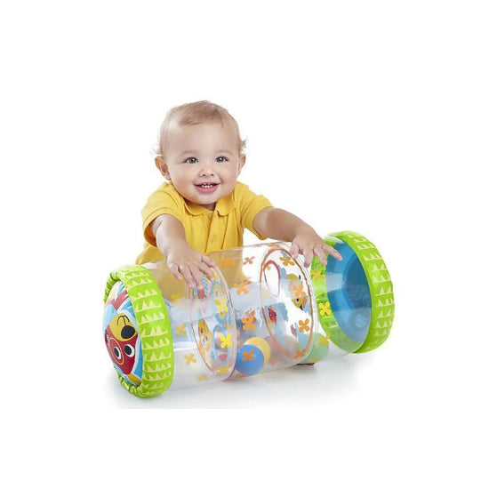 Smiling baby in yellow shirt playing with inflatable rolling toy with colorful patterns
