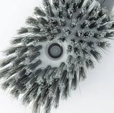 Close-up of a round grey and white cleaning brush head with dense bristles