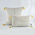 White decorative pillows with gold geometric lines and yellow tassels on a light background