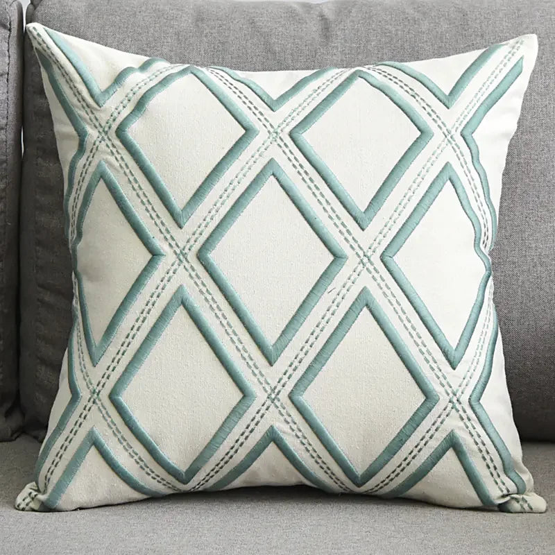 Decorative throw pillow with blue geometric diamond pattern on a grey sofa