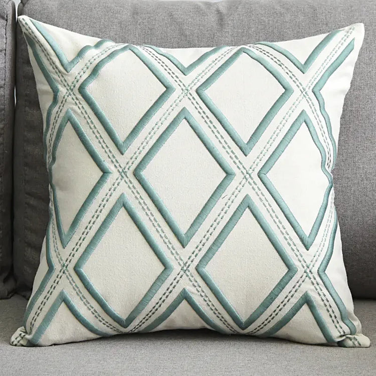 Decorative throw pillow with blue geometric diamond pattern on a grey sofa