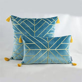 Blue velvet throw pillows with gold geometric lines and yellow tassels on a white surface
