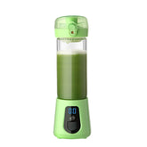 Green portable blender with digital display, filled with green smoothie, on white background.