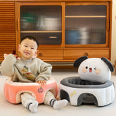 Smiling child sitting in a plush peach baby chair beside a cute dog-shaped seat in a cozy room