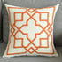 Modern beige throw pillow with orange geometric embroidery on a gray sofa