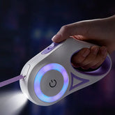 Hand holding LED retractable dog leash with light, purple accents, power button visible