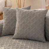 Gray quilted throw pillows with a woven pattern on a matching sofa in a modern living room