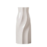 Modern white ceramic vase with wavy geometric design on plain background