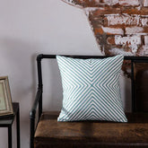 Geometric pattern throw pillow on leather bench with exposed brick wall backdrop