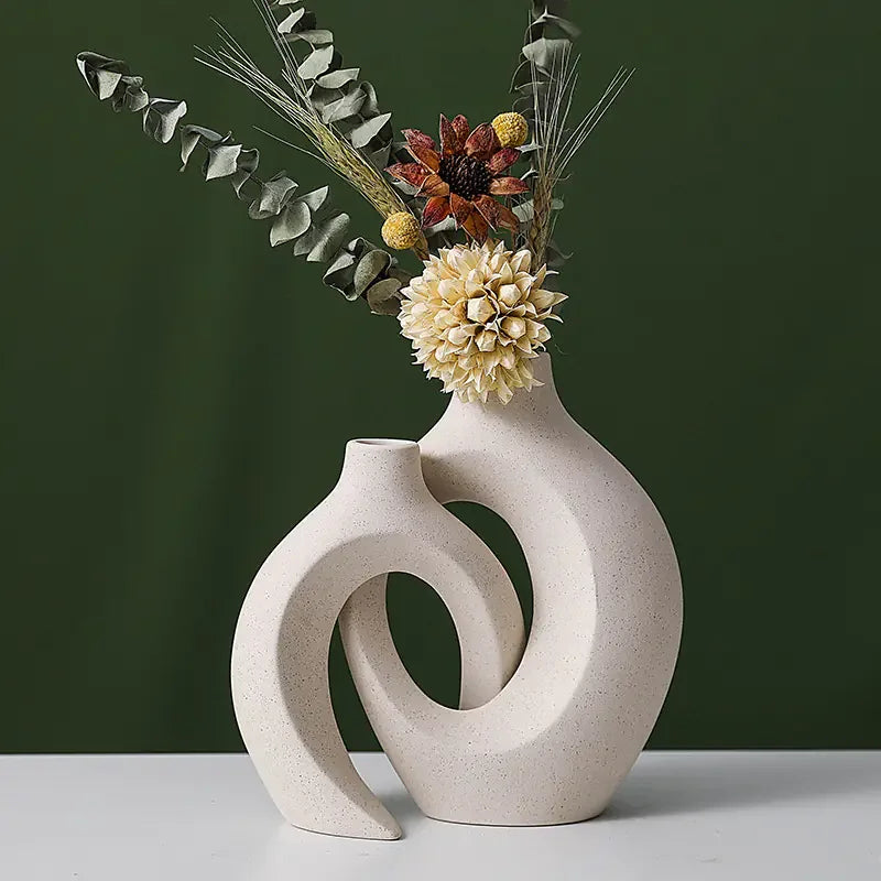 Modern ceramic abstract vase with dried flowers on white table, green background