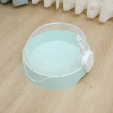 Light blue cat litter box with sifting scoop on wooden floor near white curtains
