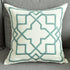 Modern decorative pillow with geometric teal embroidery on a gray sofa