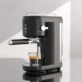 Modern black espresso machine brewing coffee on a glossy countertop in bright kitchen light