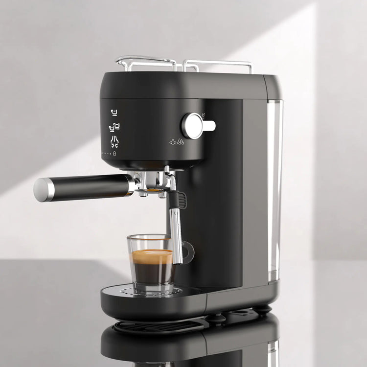 Modern black espresso machine brewing coffee on a glossy countertop in bright kitchen light
