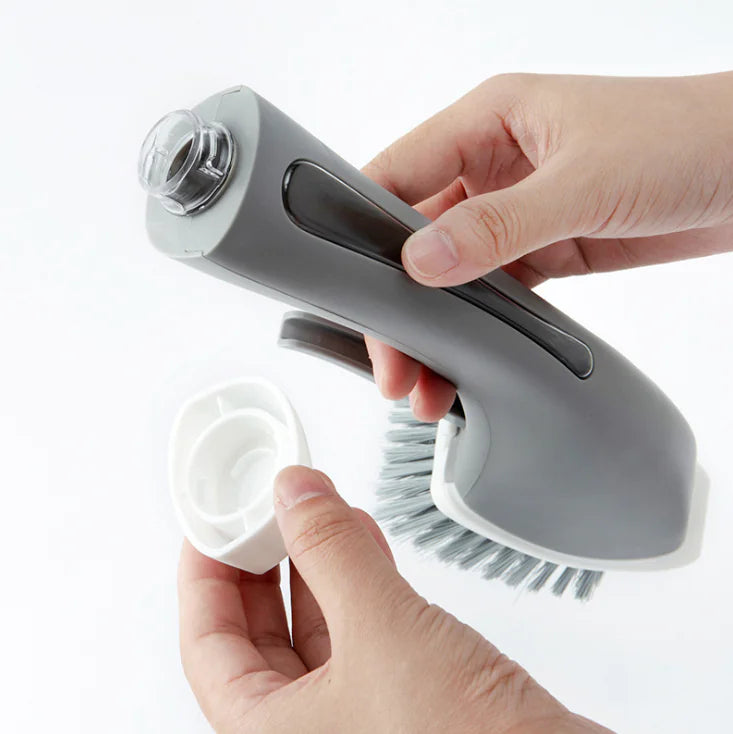 Hands assembling a gray dish brush with soap dispenser on a white background