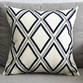 White throw pillow with black diamond geometric pattern on a grey sofa