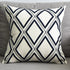 White throw pillow with black diamond geometric pattern on a grey sofa