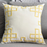 Cream throw pillow with yellow geometric pattern on a gray sofa