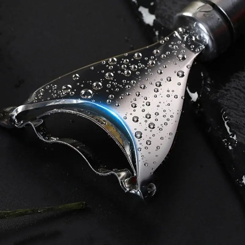 Stainless steel kitchen scraper with water droplets on black surface