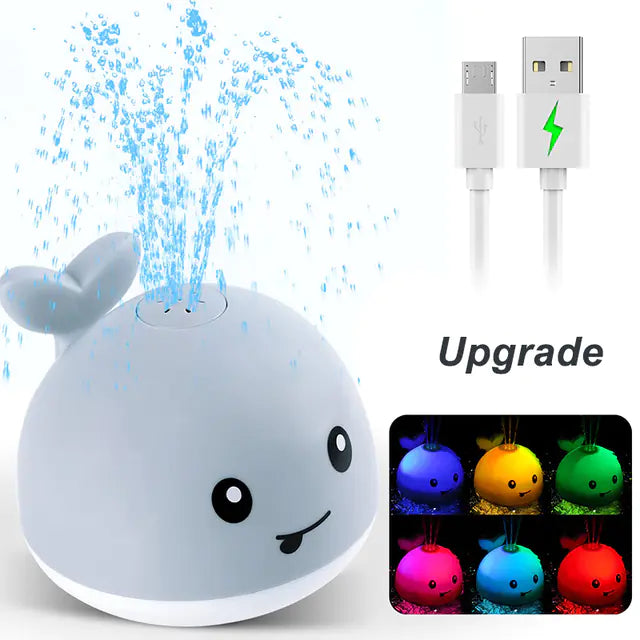Cute whale-shaped LED night light fountain toy with USB charging cable and colorful lights.