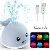 Cute whale-shaped LED night light fountain toy with USB charging cable and colorful lights.
