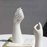 Modern white ceramic hand sculptures on a table with a book, minimalist home decor