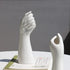 Modern white ceramic hand sculptures on a table with a book, minimalist home decor