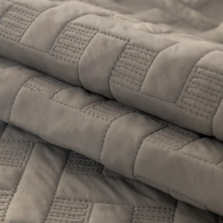 Folded grey quilted blanket with soft textured stitching detail