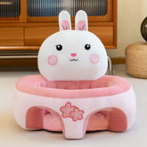 Plush pink bunny baby seat with cherry blossom design on the front, indoor setting