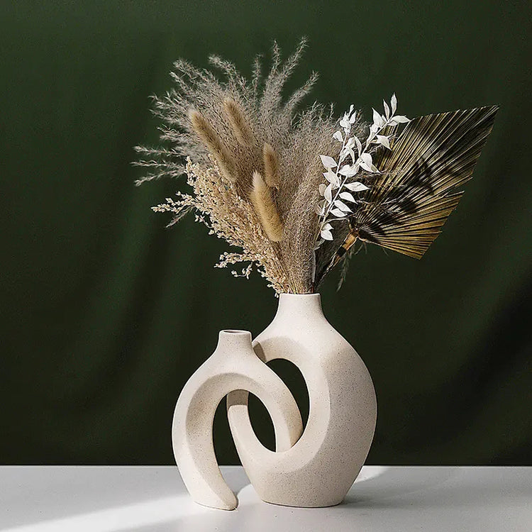 Modern abstract beige ceramic vase with dried pampas grass, palm leaf, and white foliage