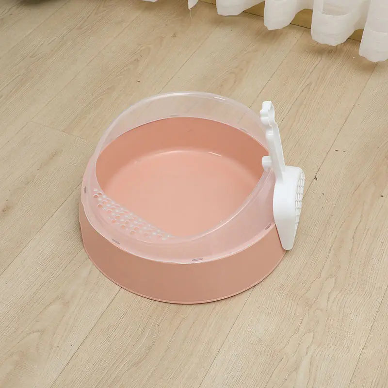 Pink plastic cat litter box with scooper on light wooden floor