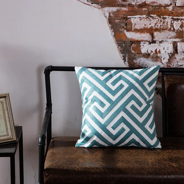 Geometric blue and white throw pillow on brown leather bench against exposed brick wall