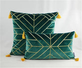 Green velvet throw pillows with gold geometric lines and yellow tassels on a white background