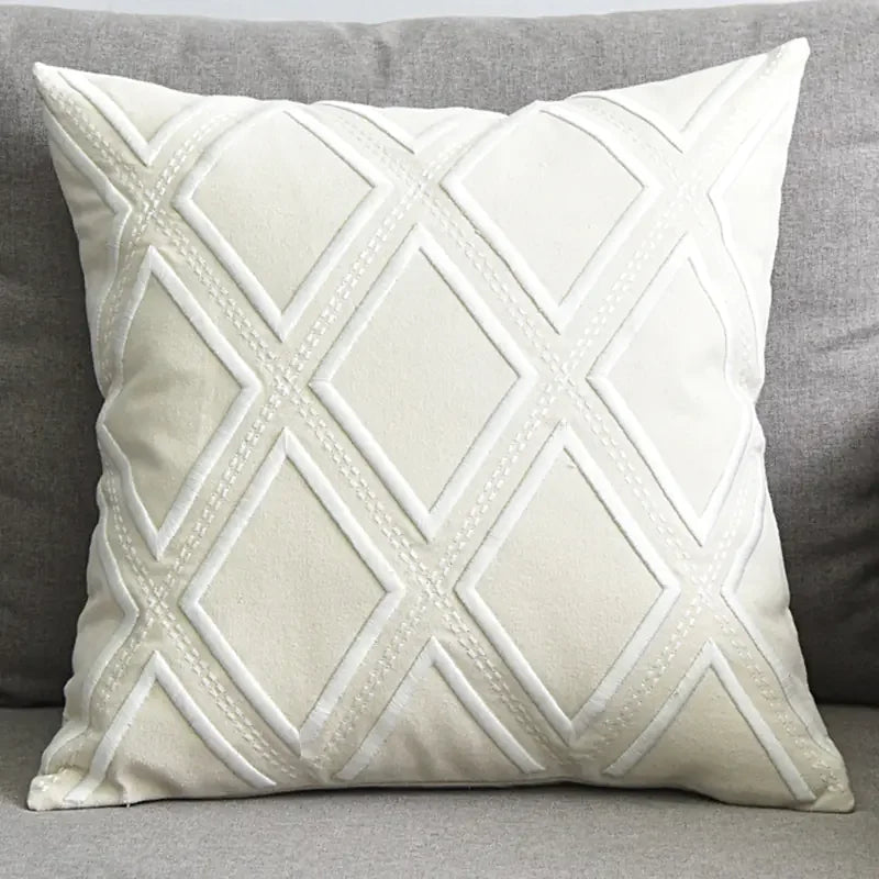 White decorative throw pillow with diamond pattern on a grey sofa