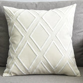 White decorative throw pillow with diamond pattern on a grey sofa