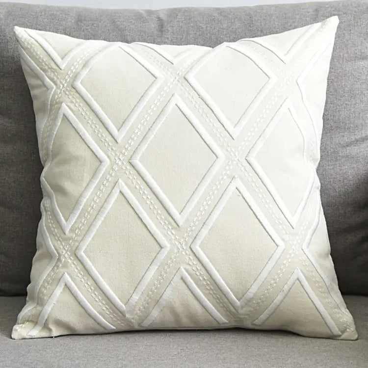 White decorative throw pillow with diamond pattern on a grey sofa