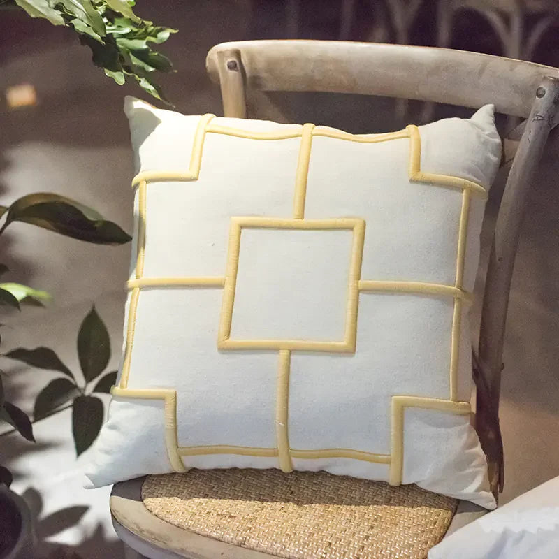 Decorative cream throw pillow with yellow geometric lines on a rustic wooden chair